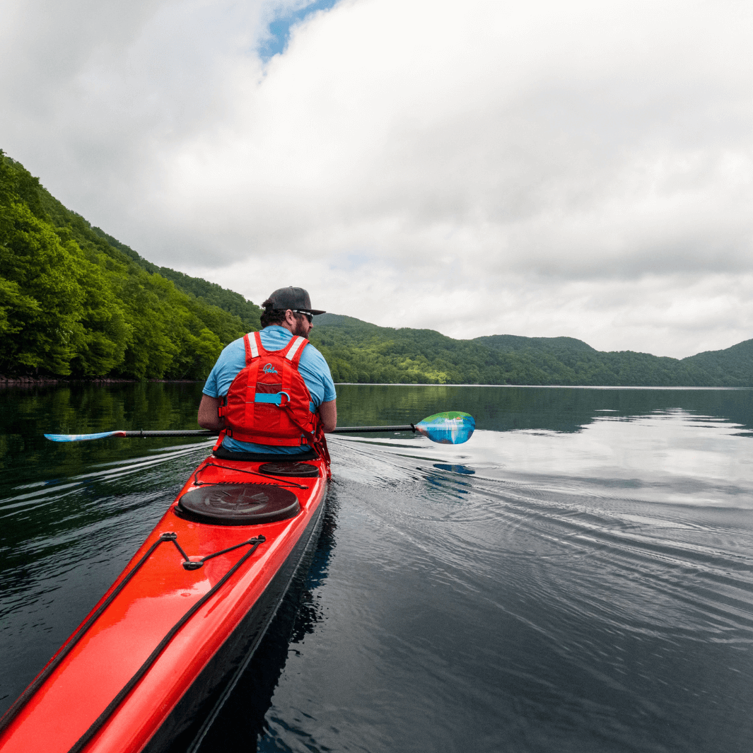 male kayaker in sea kayak paddling with whiskey northern lights#color_northern-lights