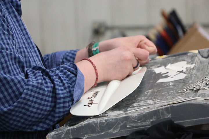 Production worker placing graphics on a paddle blade
