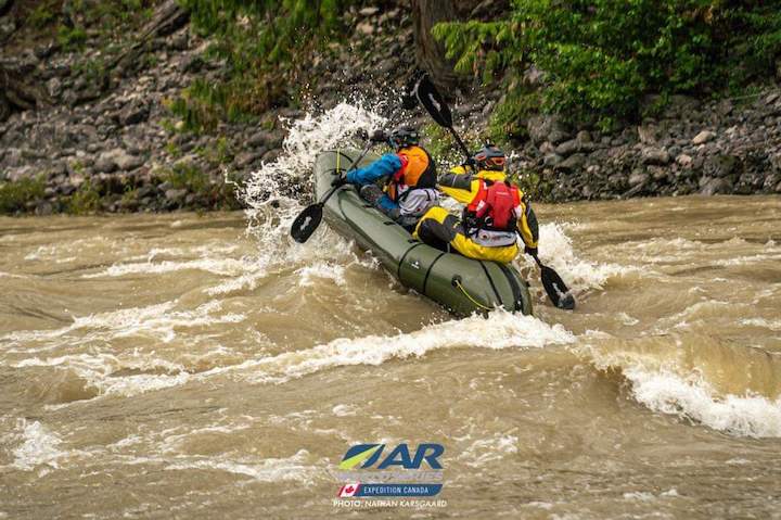 two paddlers in a tandem packraft in big rapids
