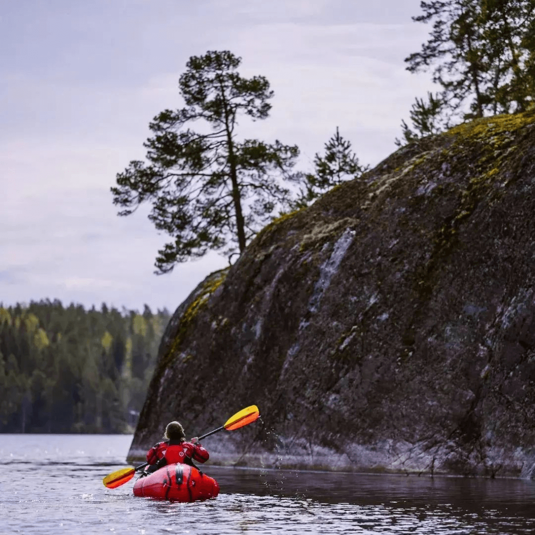 tango fiberglass 4-piece posi-lok kayak paddle fuego being paddled in packfraft along shoreline#color_fuego